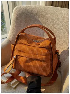 Detailed view of the brown plaid waterproof oxford cloth handbag with front pocket and dual zippers.