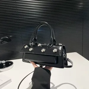Sac à main baguette en cuir vernis noir avec clous sphériques argentés et poignée élégante.