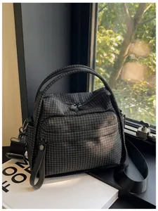 Detailed view of black grid pattern casual tote bag with handles and crossbody strap.