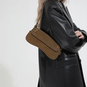 Close-up of a stylish brown studded shoulder bag worn by a model in black leather jacket.