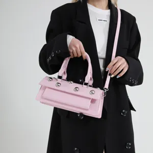 Élégant sac bandoulière baguette en cuir vernis rose avec rivets métalliques et poignée.