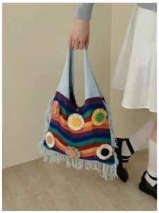 Detalle de bolso tejido de punto con rayas de arcoíris vibrantes y flores de ganchillo.