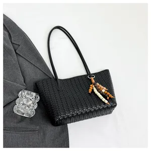 Black woven leather tote bag with long shoulder straps and wooden bead charm detail.