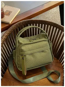 Green grid waterproof oxford cloth handbag detail, showing textured fabric and wide strap.