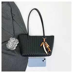 Black woven tote bag for women, stylish leather shoulder handbag with beaded charm for daily work.