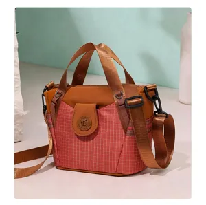 Detailed view of the stylish nylon crossbody bag featuring pink plaid pattern and brown handles.