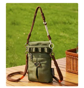 Détail de sac bandoulière à carreaux avec pendentif cœur et bandoulière en corde.