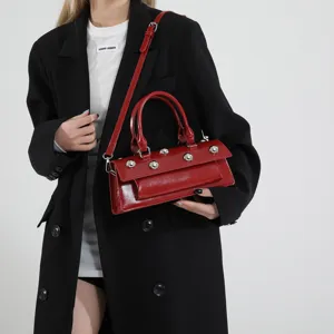 Sac épaule baguette en cuir verni rouge avec des clous métalliques pour femmes élégantes et chic.