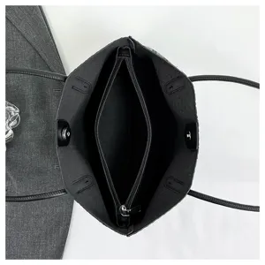 Black tote bag detail showing internal zipper compartment, lining and dual handles interior.