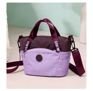 Detailed view of the small purple plaid nylon crossbody bag, featuring dual handles and adjustable strap.