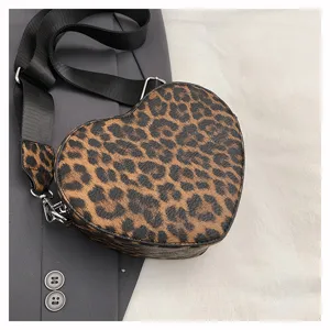 Vue détaillée du sac bandoulière tendance cœur léopard avec large sangle noire.