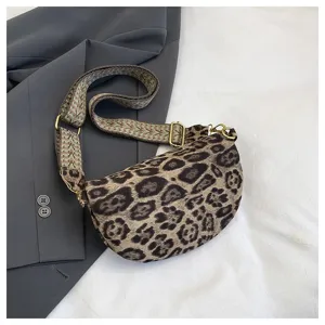 Leopard print crossbody bag detail showing trendy crescent design, wide woven strap, and hardware.