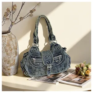Close-up of stylish washed denim shoulder bag featuring multi pockets and metallic hardware.