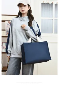 Vista detallada del bolso tote de oxford azul oscuro llevado por model, gran capacidad.
