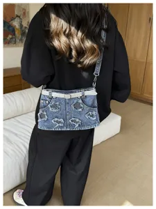 Dettaglio della borsa a tracolla in denim alla moda con gonna e cintura di strass.