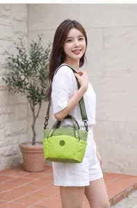 Detail view of the green plaid lightweight nylon shoulder bag with adjustable strap and front pocket.