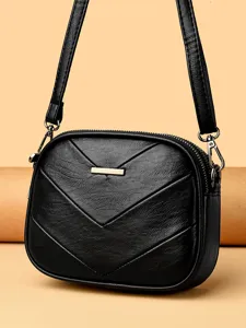 Black faux leather crossbody shoulder bag with chic chevron quilting and gold metal bar.