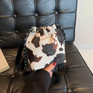 Stylish cow print bucket bag for women, trendy shoulder bag with drawstring closure and handle.