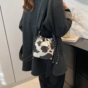 Cow print bucket shoulder bag with drawstring closure and thick strap for women daily wear.
