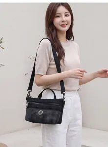 Close-up detail of a fashionable women's black plaid crossbody shoulder bag with zipper.