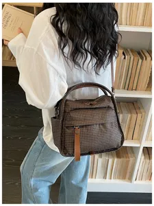 Detailed view of brown plaid oxford cloth shoulder bag in cozy bookstore library setting.