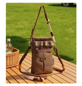 Vue détaillée du sac bandoulière outdoor à carreaux marron avec cœur et sangle en corde.