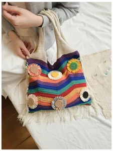 Primer plano del bolso de punto arcoíris con rayas coloridas y detalles florales.