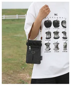 Mini sac bandoulière à carreaux noir et blanc avec lanière marron et charm cœur en métal.
