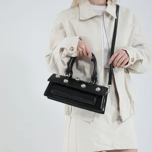 Sac bandoulière baguette en cuir verni noir avec des clous argentés pour femmes.