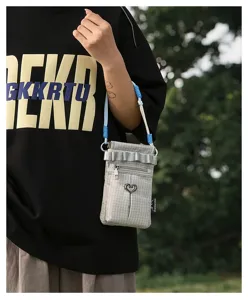 Petit sac bandoulière à carreaux gris avec pendentif cœur et lanière, vue extérieure.