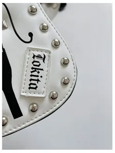 Close-up detail of white PU leather guitar shaped shoulder bag with silver metal studs.
