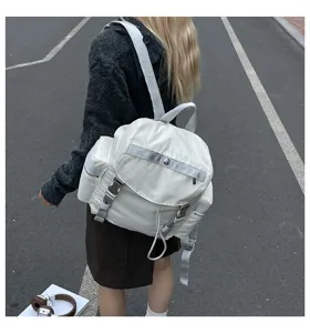 Vue détaillée du sac à dos blanc imperméable avec poches latérales et boucles métalliques.