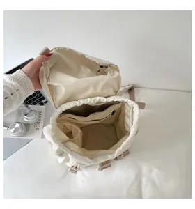 Vue détaillée de l'intérieur d'un sac à dos beige à cordon avec plusieurs poches de rangement.