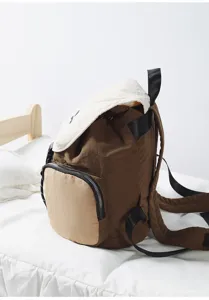 Detailed view of the brown canvas casual backpack with front pocket and contrast white flap.