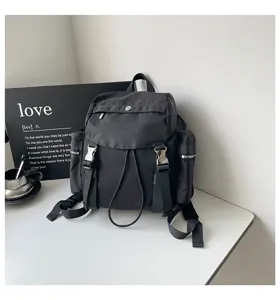 Vue détaillée d'un sac à dos en nylon noir avec poches multiples, cordon et boucles.