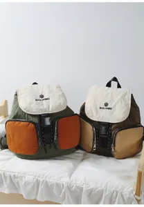 Detail view of multi-pocket contrast color casual backpack with buckle flap and zipper pockets.
