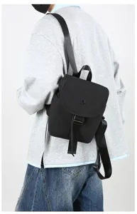 Black minimalist backpack for daily commute, lightweight travel daypack with buckle strap.