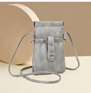 Detailed shot of gray mini phone crossbody bag with drawstring, heart charm and metal snap.
