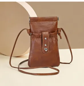 Close-up view of brown PU leather mini crossbody phone bag, showing heart charm and drawstring.