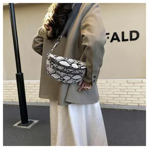 Detail shot of a stylish black and white snakeskin crossbody bag, showing texture and zippers.