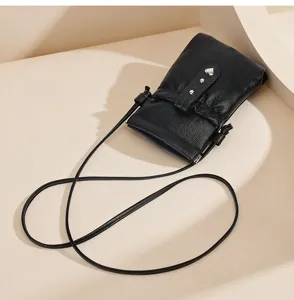 Black PU leather mini crossbody phone bag detail showing delicate metal heart and slim strap.