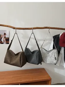 Detailed view of trendy leopard print canvas shoulder bags hanging on wooden branch.