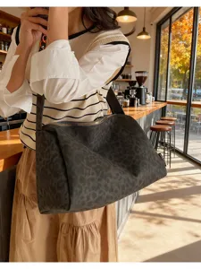 Dark leopard print canvas shoulder bag detail view in a cozy cafe scene, large capacity.