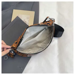 Stylish orange snakeskin crossbody dumpling bag with wide black strap and interior zipper pocket.