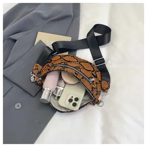Detail view of snake print crossbody bag showing spacious interior with phone and cosmetics.