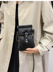 Detailed view of the black leather mini phone bag with a cute heart metal stud and drawstring.
