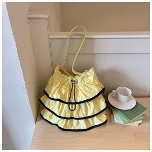 Vue détaillée d'un sac seau jaune à volants et bordure noire sur un bureau en bois.