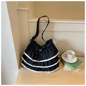 Vue rapprochée du sac seau en toile noire à volants, bordure blanche et lien coulissant.