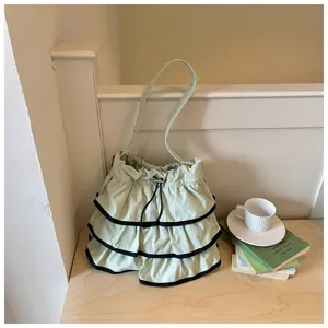 Détail de sac seau à volants vert, sac bandoulière en toile avec cordon de serrage.