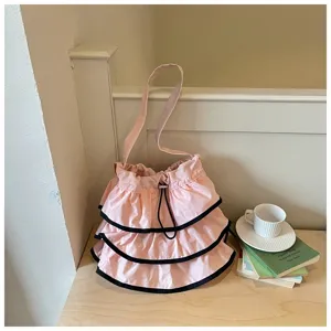 Détail de joli sac seau en toile rose à volants avec bordure noire et cordon serrage.